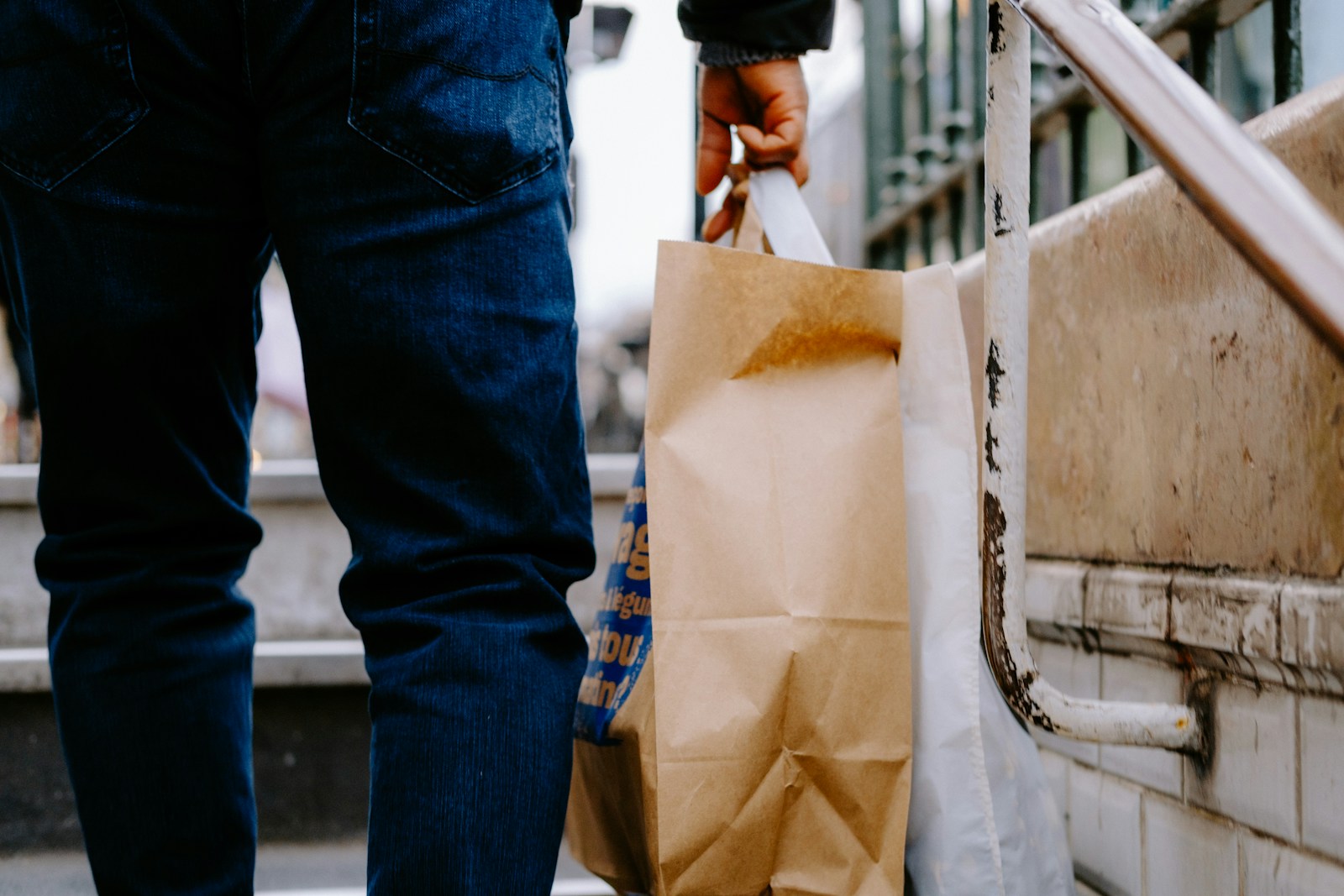 a man carrying a brown paper bag down a flight of stairs